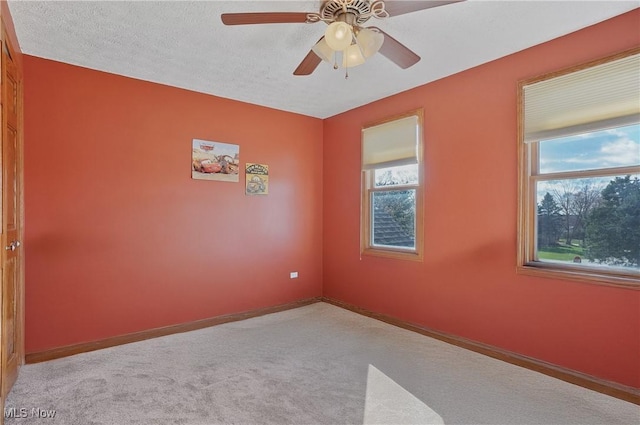 carpeted empty room featuring baseboards and ceiling fan
