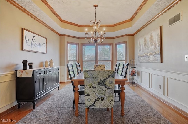 dining space featuring a tray ceiling, wood finished floors, and visible vents