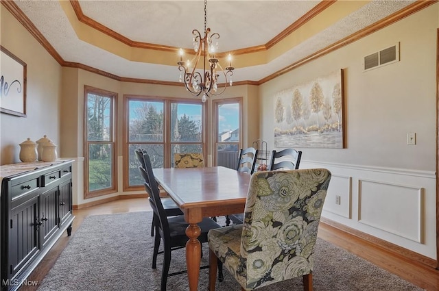 dining space with an inviting chandelier, dark wood-style flooring, visible vents, and a raised ceiling