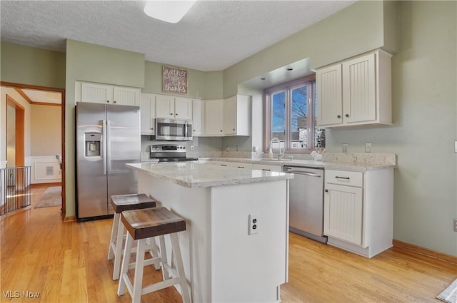 kitchen featuring light wood finished floors, white cabinets, and appliances with stainless steel finishes
