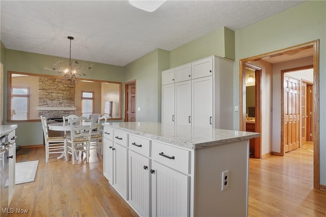 kitchen featuring white cabinets, light stone counters, a kitchen island, and light wood-type flooring