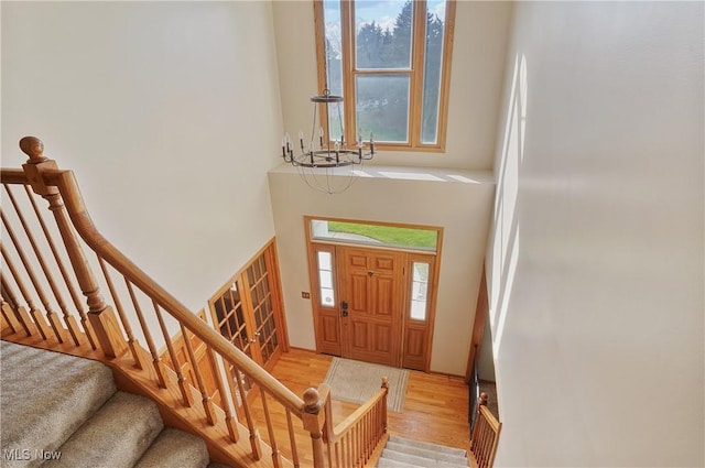 entrance foyer with light wood-type flooring, a high ceiling, a notable chandelier, and stairway