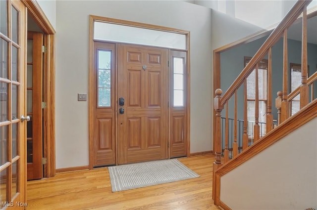 entrance foyer featuring stairway, light wood finished floors, baseboards, and plenty of natural light