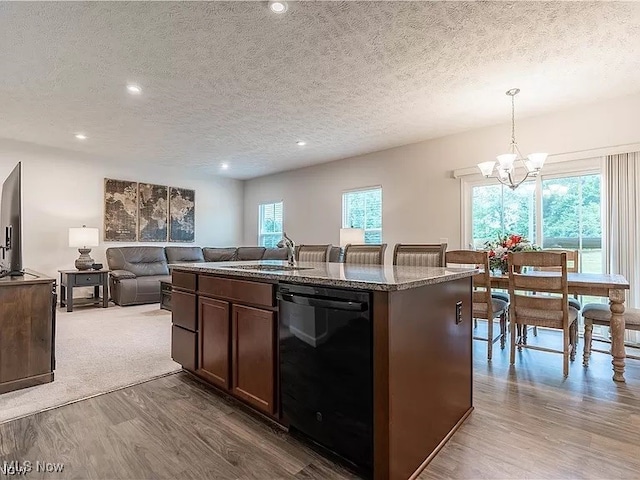kitchen with black dishwasher, wood finished floors, a textured ceiling, and an inviting chandelier