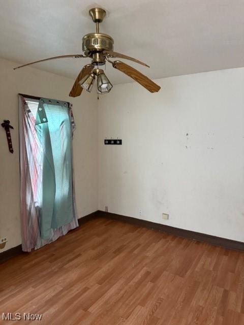 spare room featuring baseboards, a ceiling fan, and light wood-type flooring