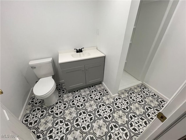 bathroom featuring toilet, baseboards, tile patterned flooring, vanity, and a walk in shower
