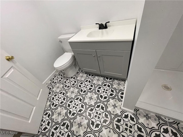 bathroom featuring tile patterned floors, toilet, baseboards, a shower stall, and vanity