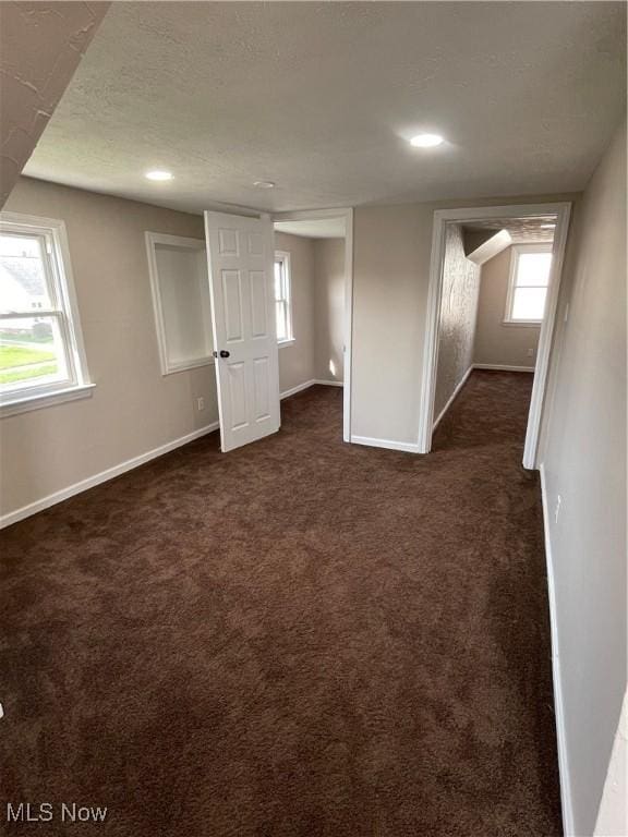 below grade area featuring baseboards, dark carpet, and recessed lighting