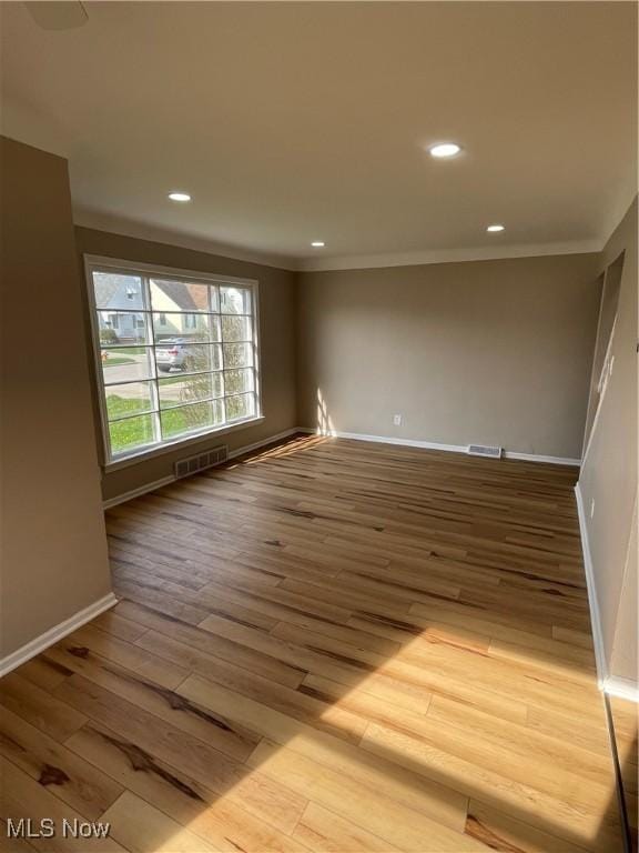 spare room featuring recessed lighting, wood finished floors, visible vents, and baseboards