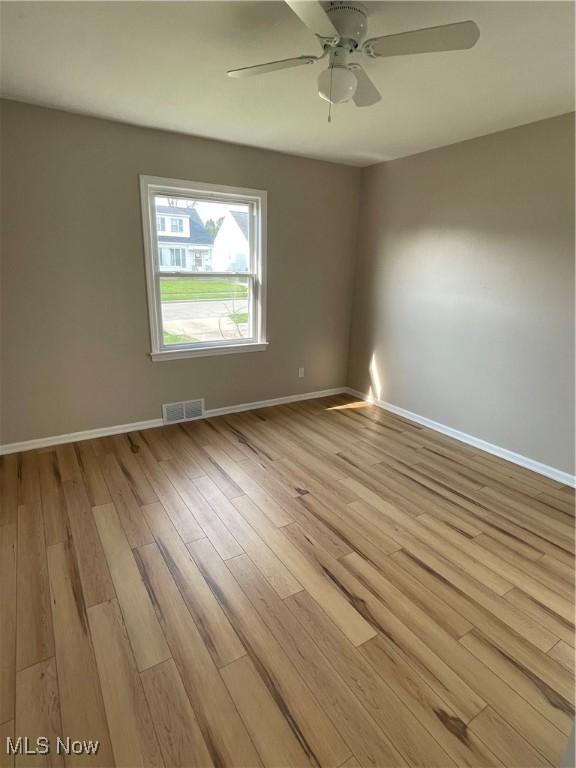 unfurnished room with light wood-type flooring, visible vents, baseboards, and ceiling fan