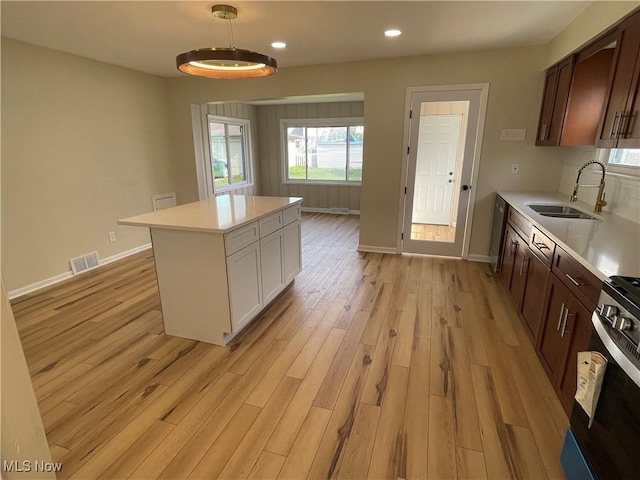 kitchen with light countertops, visible vents, a sink, light wood-type flooring, and baseboards