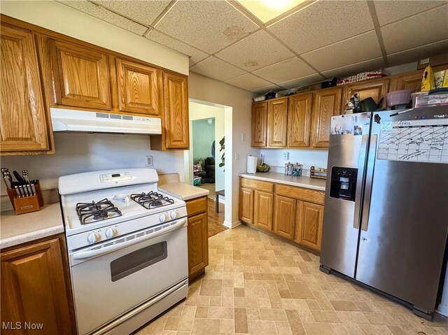 203 57th St, Vienna, WV 26105 - kitchen featuring stainless steel fridge, gas range gas stove, a drop ceiling, brown cabinets, and under cabinet range hood