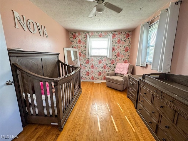203 57th St, Vienna, WV 26105 - bedroom with baseboards, a textured ceiling, wallpapered walls, and light wood-style flooring