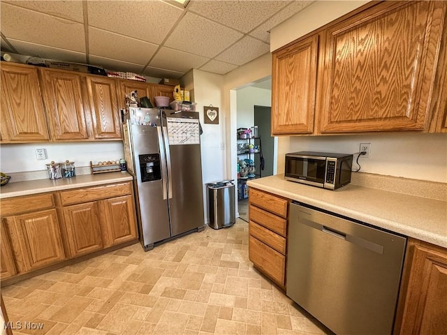 203 57th St, Vienna, WV 26105 - kitchen featuring stainless steel appliances, a paneled ceiling, light countertops, and brown cabinets