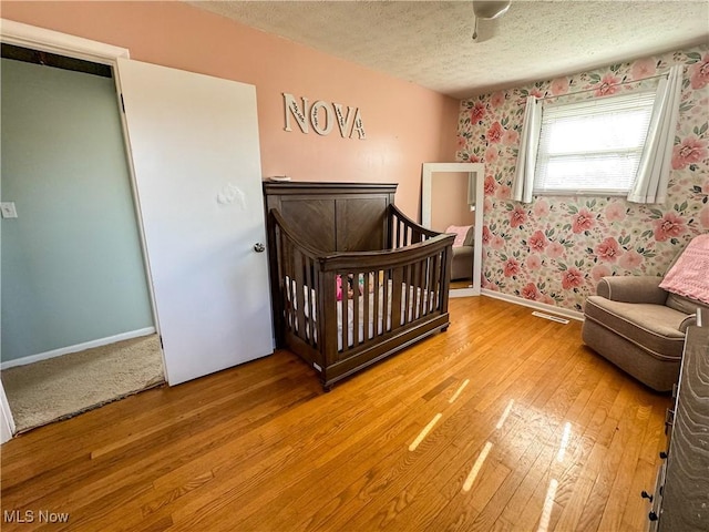 203 57th St, Vienna, WV 26105 - bedroom with a textured ceiling, wallpapered walls, light wood-style flooring, baseboards, and visible vents