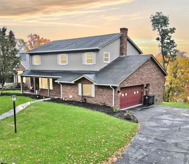 view of front facade with a chimney, a front lawn, driveway, a porch, and a garage