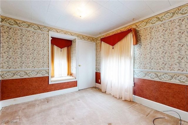spare room with baseboards, crown molding, carpet flooring, and wallpapered walls
