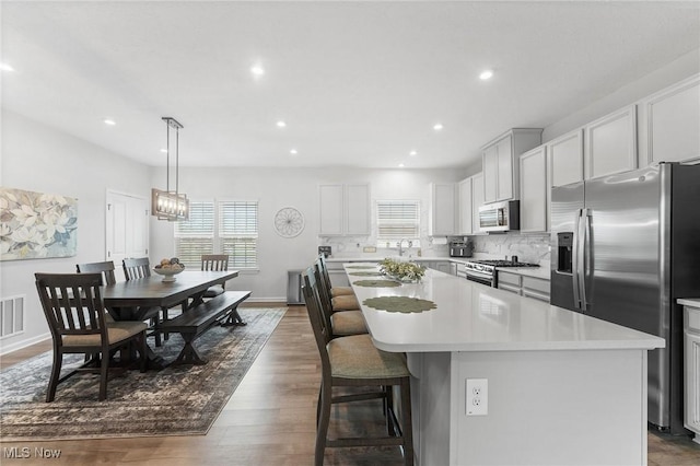 4006 N Steels Cir, Stow, OH 44224 - kitchen featuring stainless steel appliances, a center island, light countertops, backsplash, and a breakfast bar