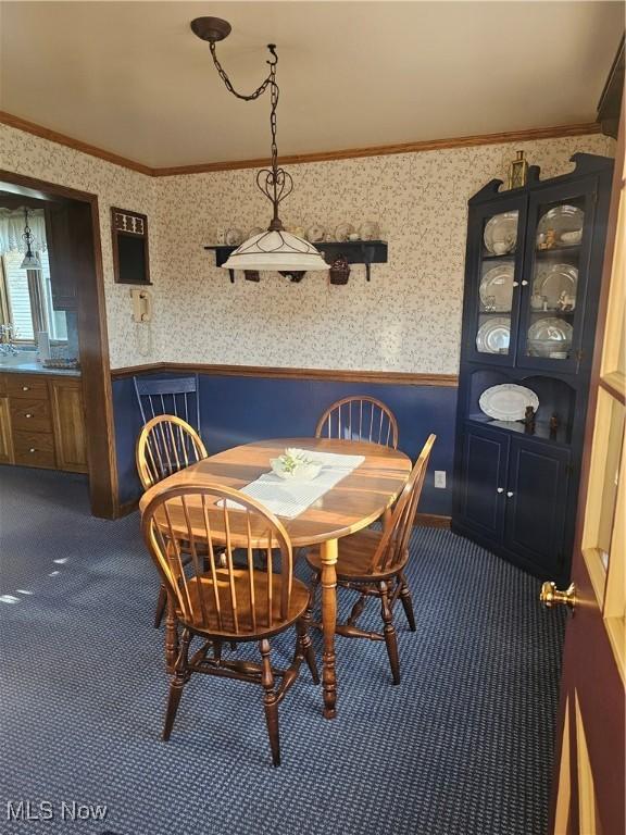 445 N 18th St, Sebring, OH 44672 - dining area featuring dark carpet, ornamental molding, a wainscoted wall, and wallpapered walls