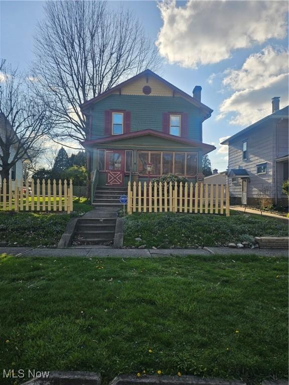 445 N 18th St, Sebring, OH 44672 - view of front of house with a sunroom, a front yard, and fence