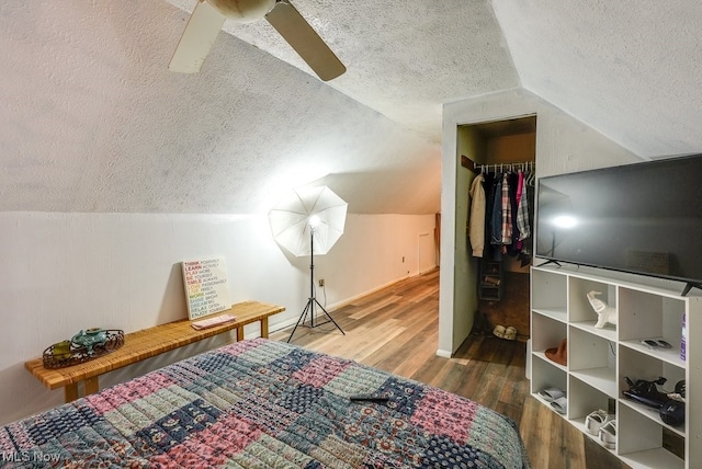 1865 9th St SW, Akron, OH 44314 - bedroom featuring a textured ceiling, vaulted ceiling, a ceiling fan, wood finished floors, and a walk in closet