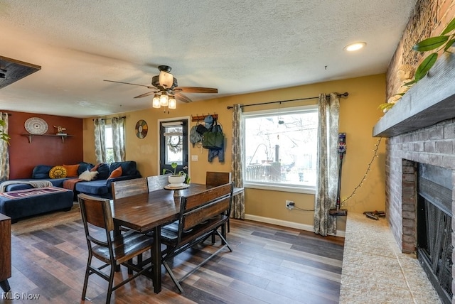 1865 9th St SW, Akron, OH 44314 - dining space with wood finished floors, a ceiling fan, a brick fireplace, and a textured ceiling