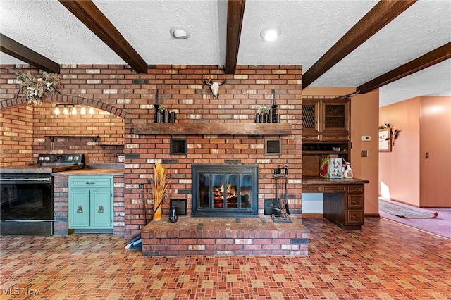 unfurnished living room featuring beamed ceiling, baseboards, a brick fireplace, and a textured ceiling