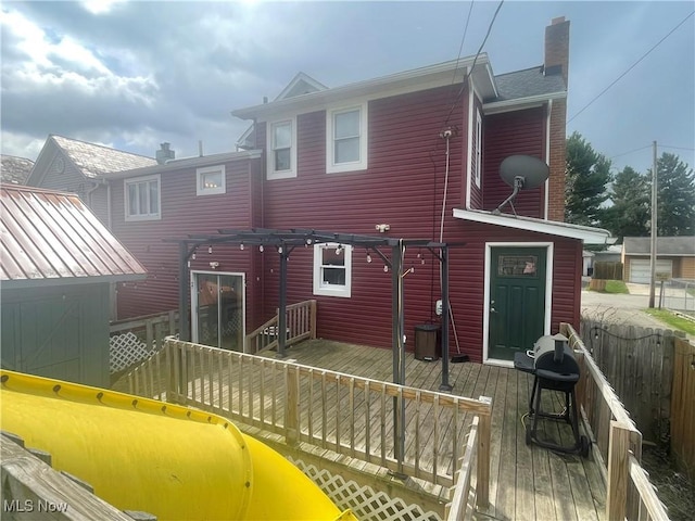 rear view of house featuring a chimney and a wooden deck