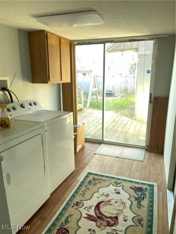 laundry room with washer and dryer, light wood-style floors, and cabinet space