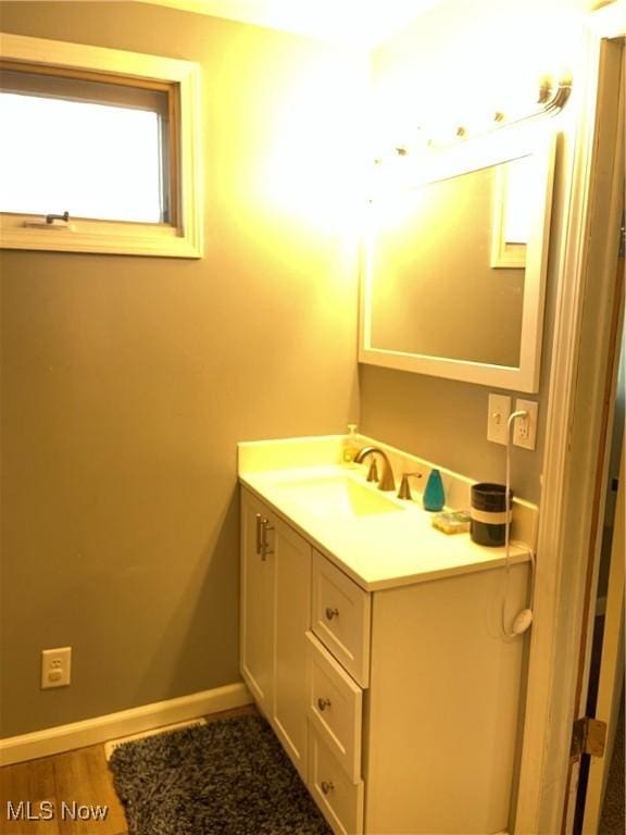 bathroom with wood finished floors, baseboards, and vanity