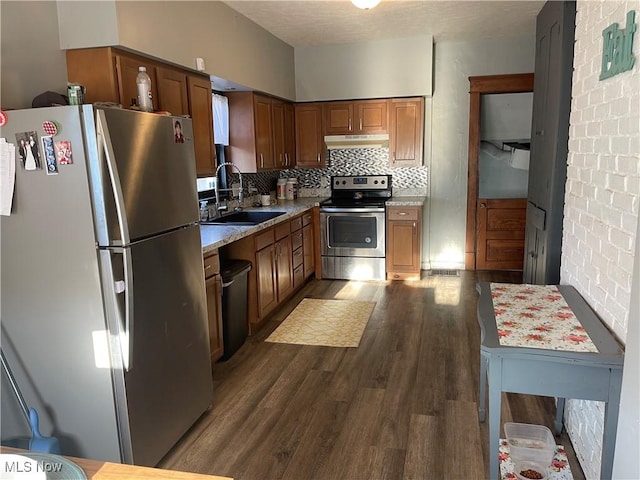 kitchen featuring stainless steel appliances, a sink, dark wood-style flooring, backsplash, and under cabinet range hood