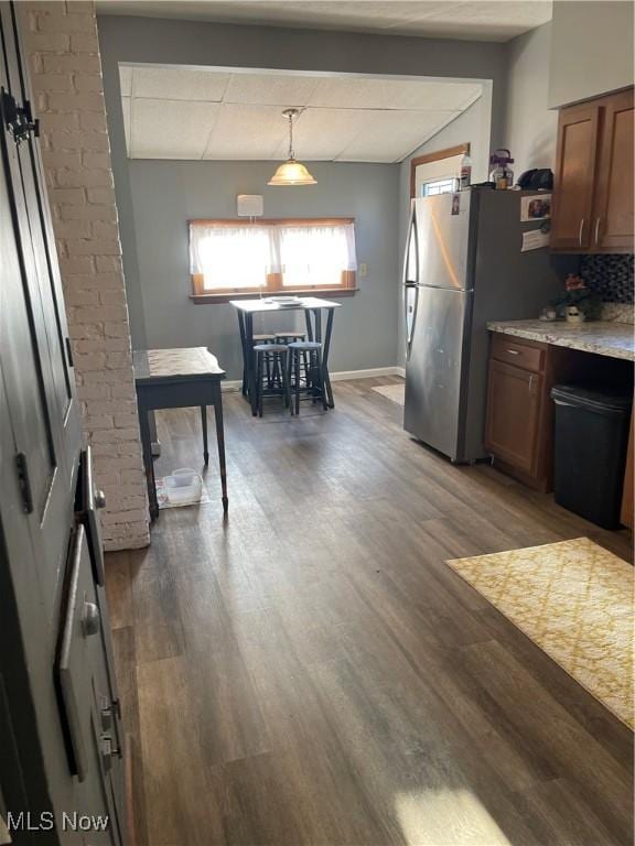 kitchen featuring freestanding refrigerator, a healthy amount of sunlight, baseboards, and dark wood-style floors