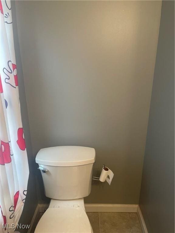 bathroom with baseboards, tile patterned flooring, and toilet