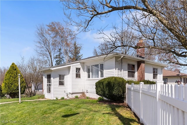 view of front of home featuring a chimney, a front lawn, and fence