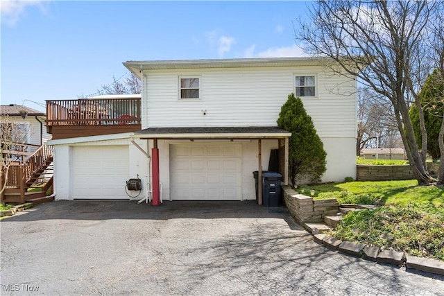 exterior space with an attached garage, aphalt driveway, and a deck
