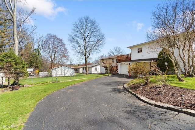 view of front of home featuring aphalt driveway, fence, a garage, and a front yard