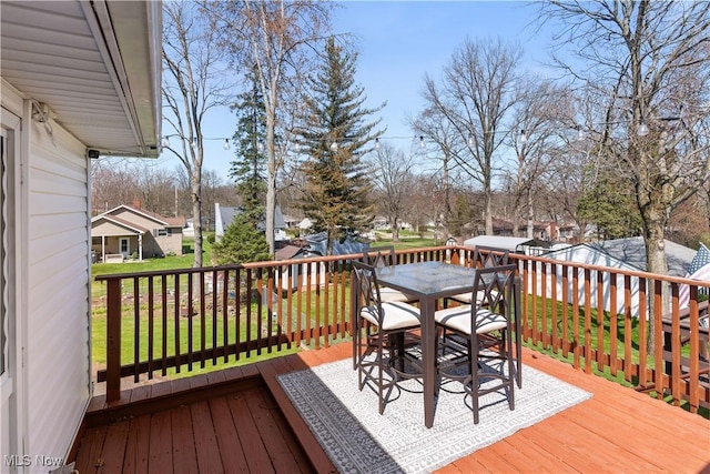 deck with a yard, outdoor dining space, and a residential view