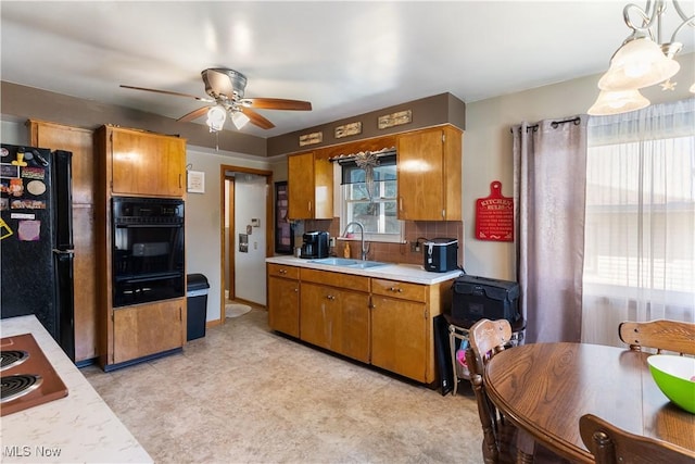 kitchen with a sink, brown cabinets, ceiling fan, light countertops, and black appliances