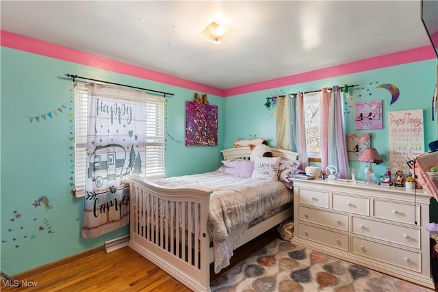 bedroom with wood finished floors, baseboards, and multiple windows