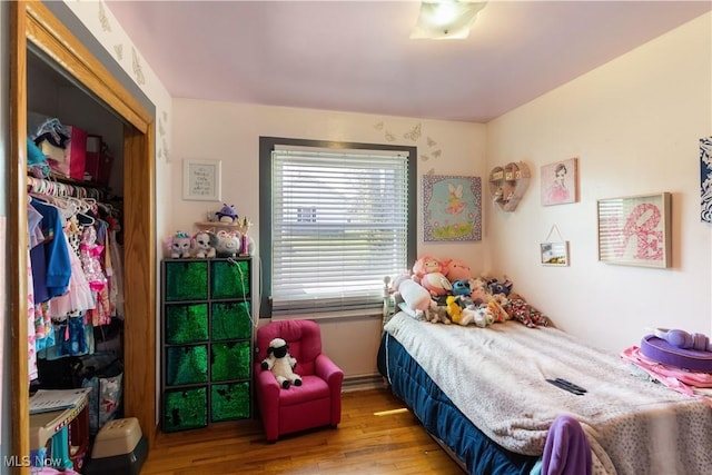 bedroom with wood finished floors and a closet