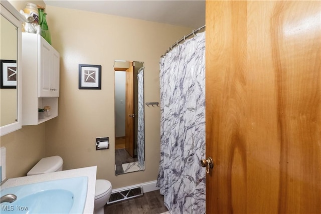 full bathroom featuring toilet, visible vents, wood finished floors, a shower with shower curtain, and vanity