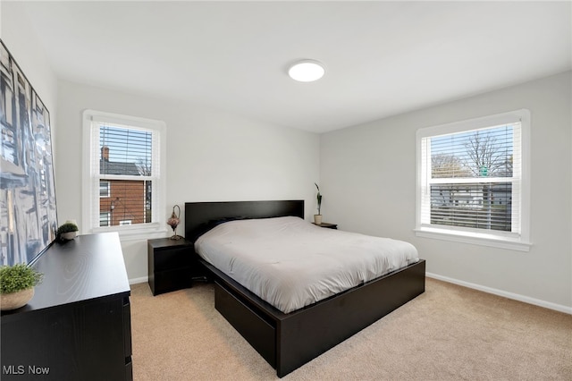 bedroom with light colored carpet, baseboards, and multiple windows