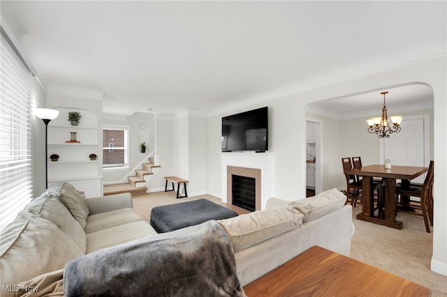 living room featuring arched walkways, a healthy amount of sunlight, light colored carpet, and an inviting chandelier