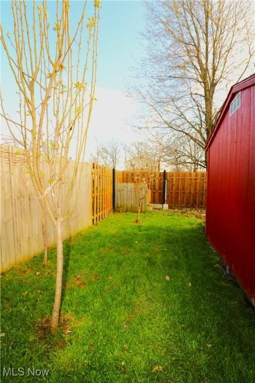 view of yard with a fenced backyard and an outbuilding