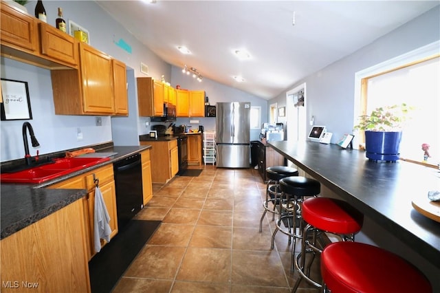 kitchen with dark countertops, a sink, black appliances, lofted ceiling, and tile patterned flooring