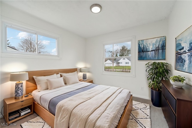 bedroom featuring baseboards, light colored carpet, and multiple windows