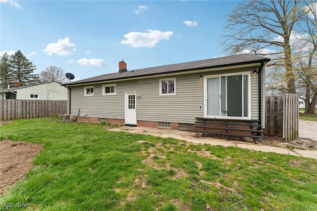 back of property featuring entry steps, a lawn, a chimney, and fence