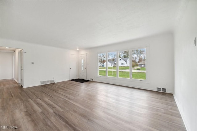 unfurnished living room with baseboards, wood finished floors, and visible vents