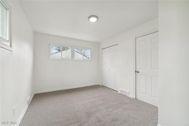 unfurnished bedroom featuring carpet floors, a closet, visible vents, and baseboards