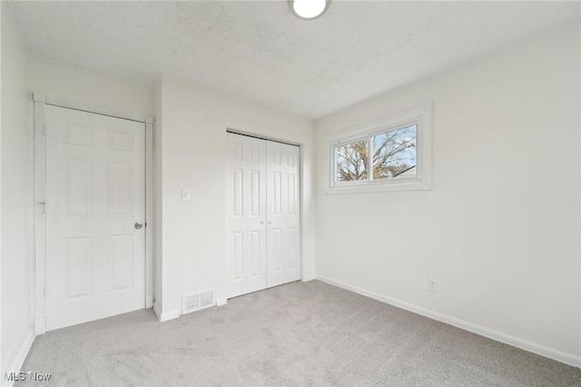 unfurnished bedroom featuring carpet, visible vents, and baseboards